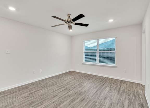 A room with a ceiling fan and a window with blinds.