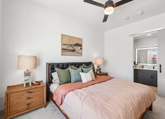 A bedroom with a bed, nightstand, and a ceiling fan.