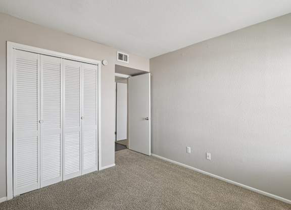 A room with a white door and a carpeted floor.
