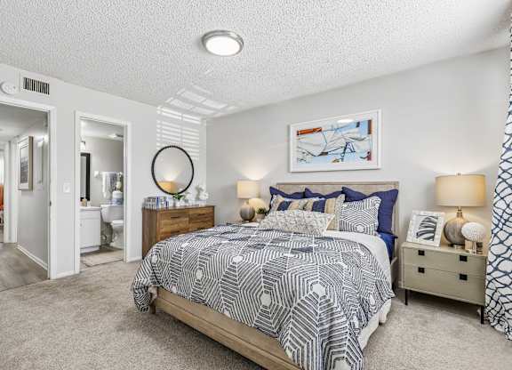 A bedroom with a bed, nightstand, and lamp.