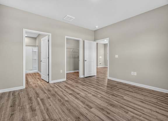 A room with three open doors and wood flooring.
