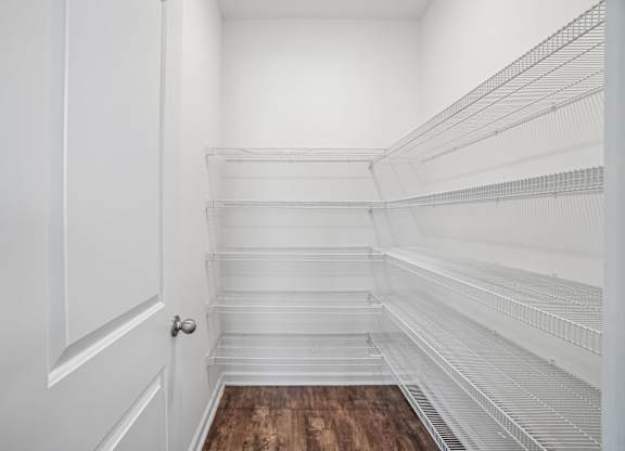 Empty white pantry with a door on the left.