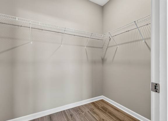 A white closet with a wooden floor and a white door.