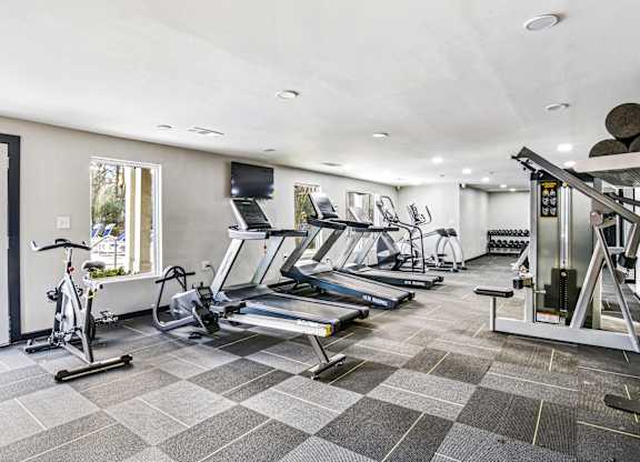 A spacious gym with treadmills, elliptical machines, and a stationary bike.