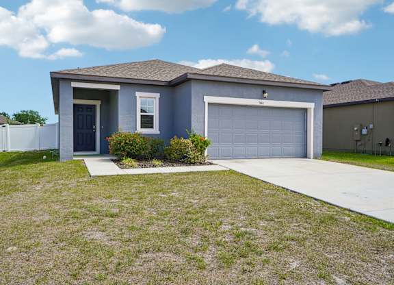 A house with a blue garage door and a white fence.