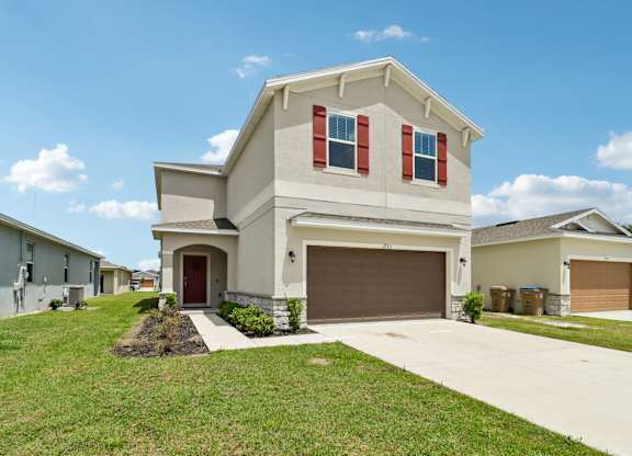 A house with a brown garage door and red shutters.