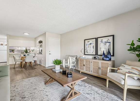 A living room with a white couch, a wooden coffee table, and a dining table with chairs.