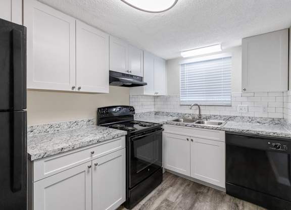 Kitchen with black appliances, ample cabinet space, and a window providing good lighting at Townsend Apartments in Jacksonville near Atlantic Beach, Florida.