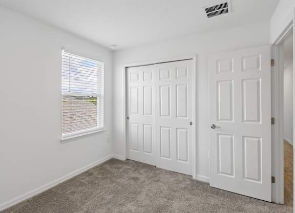 A room with two doors and a window with blinds.