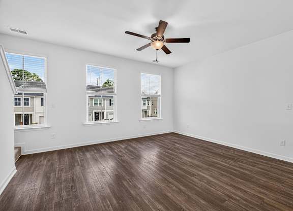A room with a ceiling fan and wooden flooring.