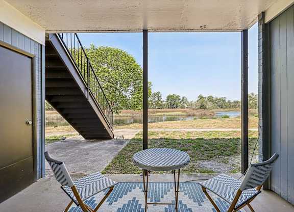 A patio with a table and chairs overlooking a river.