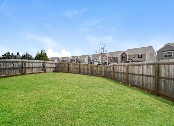 A backyard with a wooden fence and a green lawn.