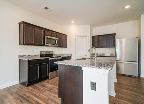 A kitchen with a granite countertop and stainless steel appliances.