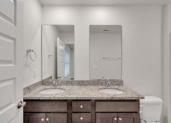 A bathroom with a granite countertop and a white toilet.