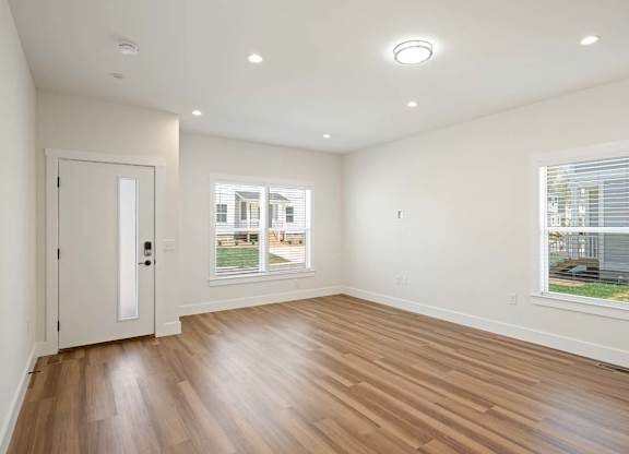 Spacious and bright living area with wood flooring and large windows in an Asheville home.