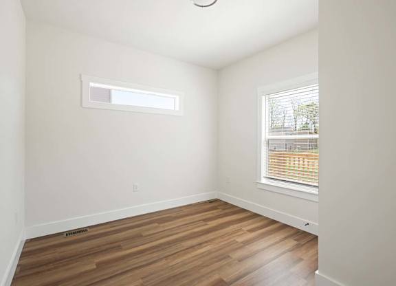 A room with wooden floors and a window with blinds.