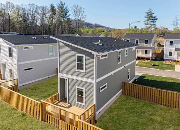 Aerial view of a fenced two-story home in Asheville with private yard and modern gray siding.