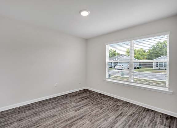 A room with a window and a view of a house and a car outside.