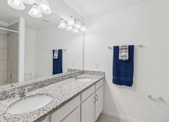 A bathroom with a granite countertop and two sinks.