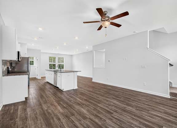 A spacious kitchen with white cabinets and a wooden floor.