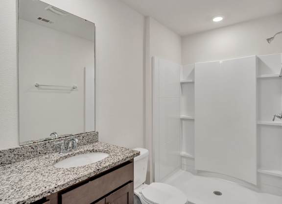 A white bathroom with a sink, toilet, and shower.