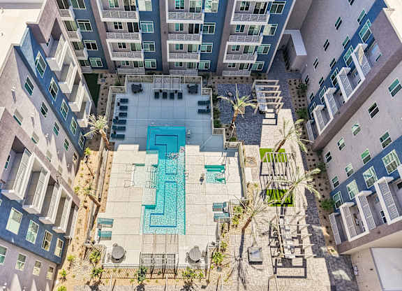 A swimming pool surrounded by buildings and palm trees.