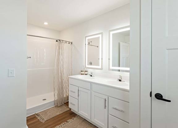 A white bathroom with a tub, sink, and mirror.