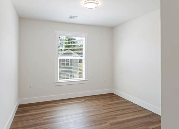 A room with a window and wooden flooring.