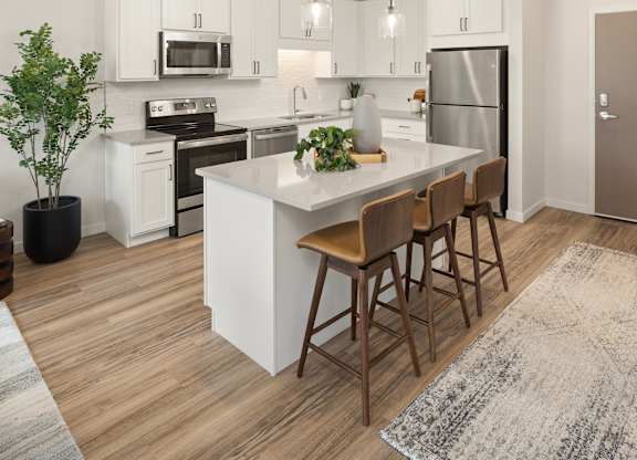 A kitchen with a white island and wooden bar stools.