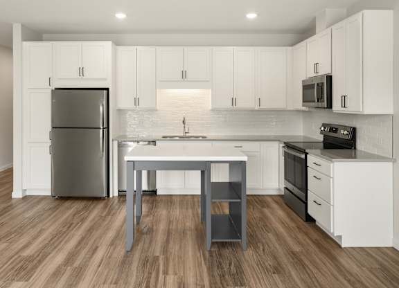 A modern kitchen with white cabinets and a wooden floor.