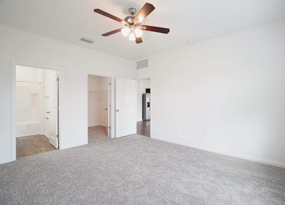 A room with a ceiling fan and carpeted floor.