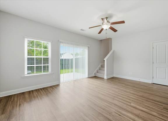 A room with a ceiling fan and wooden flooring.