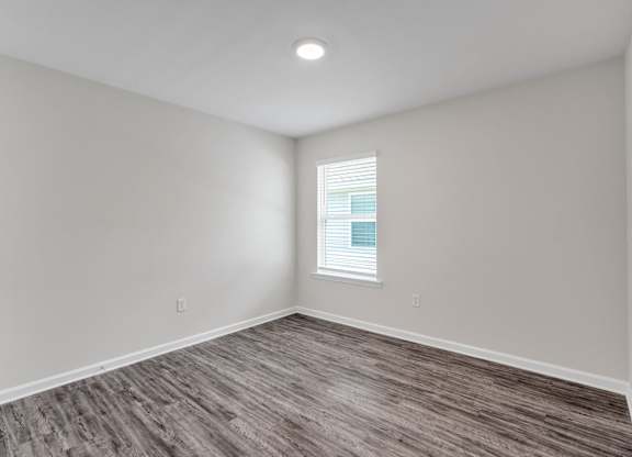 A room with a window and wooden flooring.