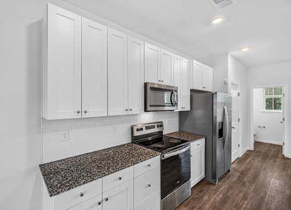 A kitchen with white cabinets and a granite countertop.