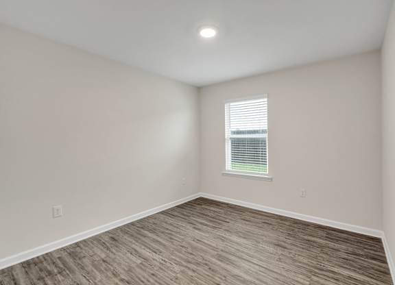 A room with a window and wooden flooring.