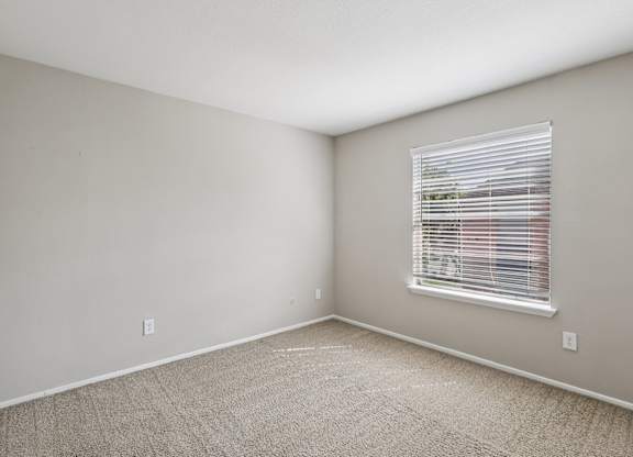A room with a window and carpeted floor.