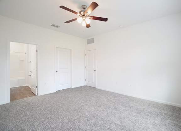 A room with a ceiling fan and carpeted floor.
