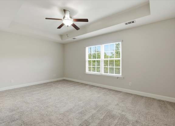 A room with a ceiling fan and a window with blinds.