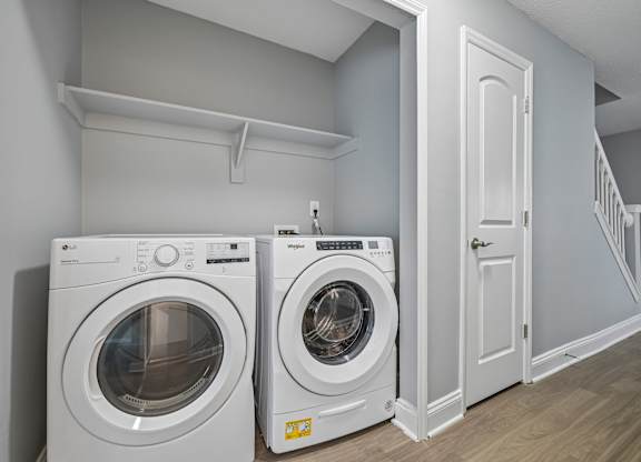 Two white front load washing machines in a laundry room.