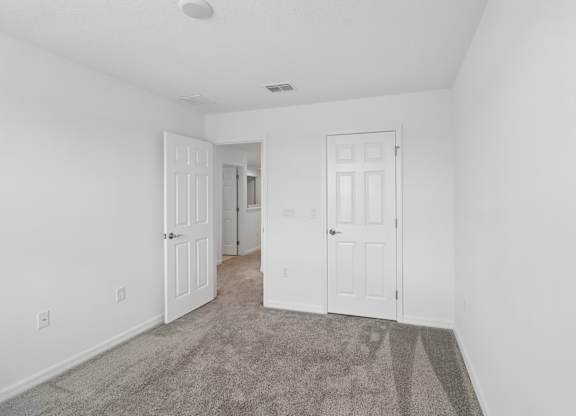 A room with two white doors and a carpeted floor.