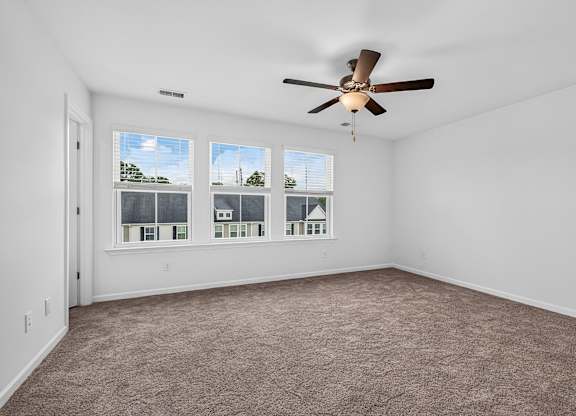 A room with a ceiling fan and carpeted floor.