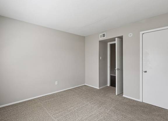 A room with a carpeted floor and two doors.