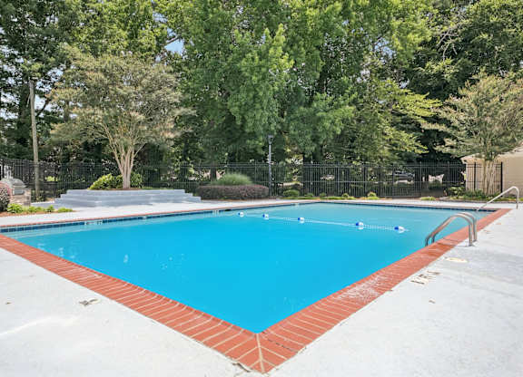 A rectangular pool with a red border and a metal fence around it.