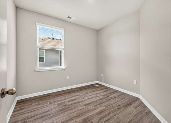 A room with a window and wooden flooring.