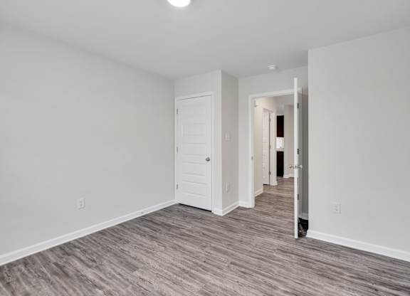 A room with a white door and a grey floor.