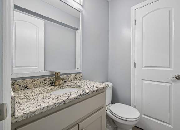 A bathroom with a granite countertop and white fixtures.