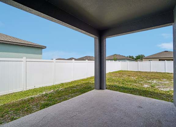 A concrete patio with a white fence and a house in the background.