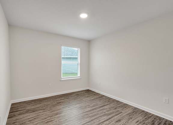A room with a window and wooden flooring.