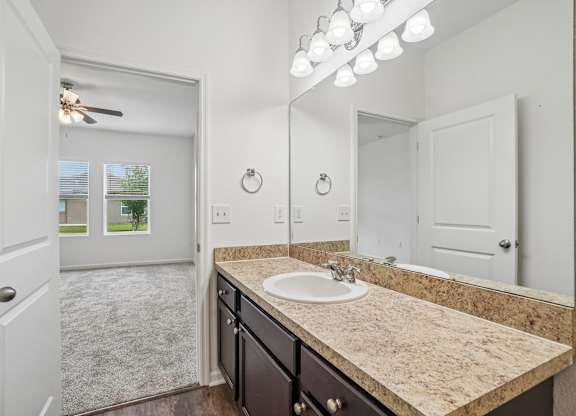A bathroom with a sink, mirror, and a ceiling fan.