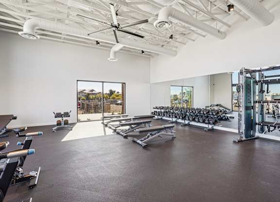 A gym with a row of treadmills and a fan.